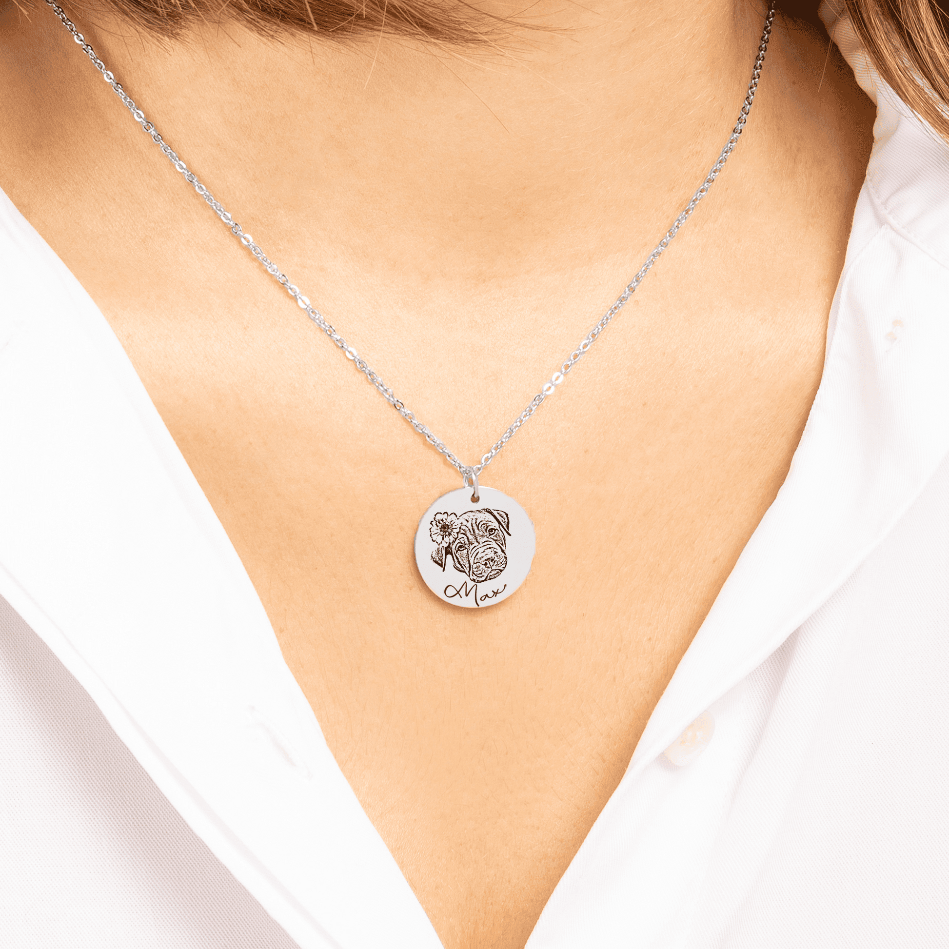 A custom dog portrait necklace showing a detailed engraved image of a dog's face on a silver-tone circular pendant.